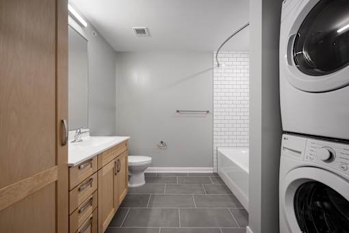 A modern bathroom with a washer and dryer built in.