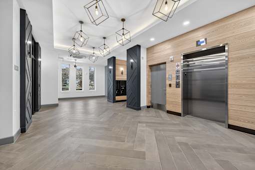A modern hallway with wooden floors and a black elevator.