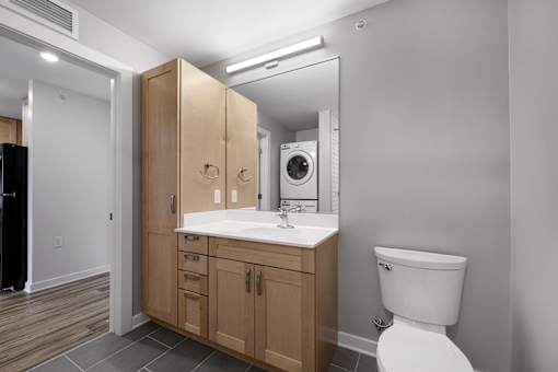 A bathroom with a white toilet, a sink with a mirror above it, and a wooden cabinet.