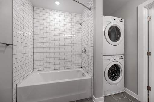 A white tiled bathroom with a washer and dryer.