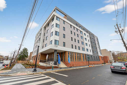 A modern building with a flat roof and a balcony on the second floor.