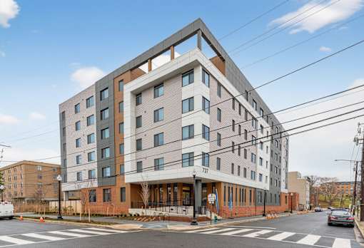 A large building with a lot of windows is in the middle of a street.