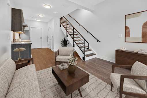 A living room with a brown sofa, a coffee table, and a staircase.