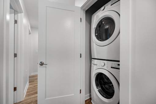 A white door is open to reveal a white washing machine.