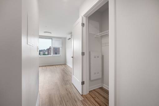 A white room with a doorway leading to a kitchen.