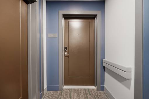 A brown door with a silver handle is in the center of the image.