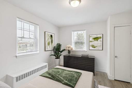 a bedroom with a bed and a dresser and two windows