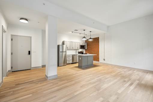 A kitchen area with a refrigerator, cabinets, and a microwave.