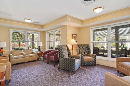 A living room with a purple carpet and a variety of chairs and couches.