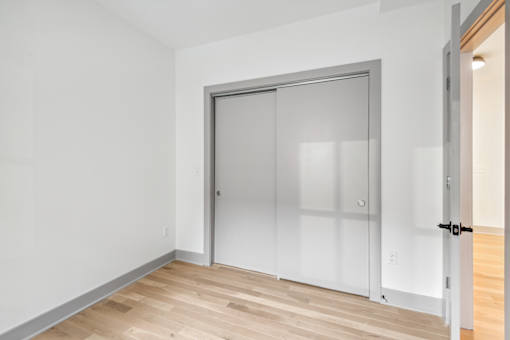 A room with a white door and a wooden floor.