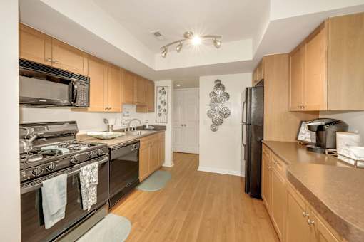 A kitchen with wooden cabinets and a black refrigerator.