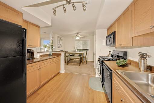 A kitchen with wooden cabinets and a black refrigerator.