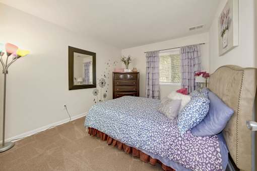 A bedroom with a bed, nightstand, and lamp.