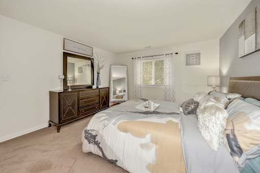 A bedroom with a bed, nightstand, and dresser.
