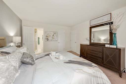 A bedroom with a large bed and a wooden dresser.