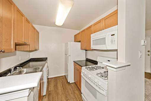 A kitchen with white appliances and wooden cabinets.