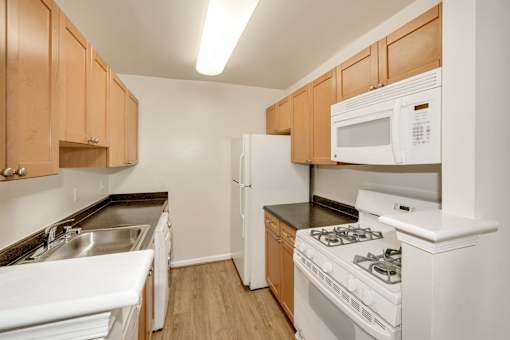 A kitchen with white appliances and wooden cabinets.