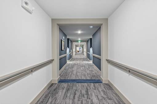 A long hallway with a blue carpet and white walls.