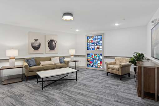 A living room with a couch, two chairs, a coffee table, and a stained glass window.