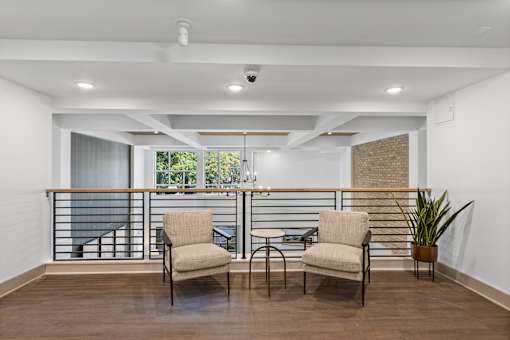 Two chairs are placed on a balcony with a table between them.