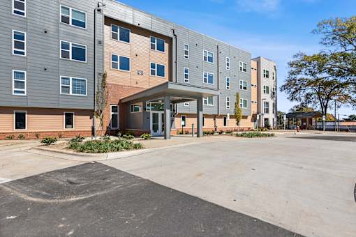A parking lot in front of a multi-story apartment building.