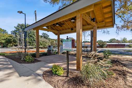 A wooden shelter with a signboard is situated in a landscaped area.