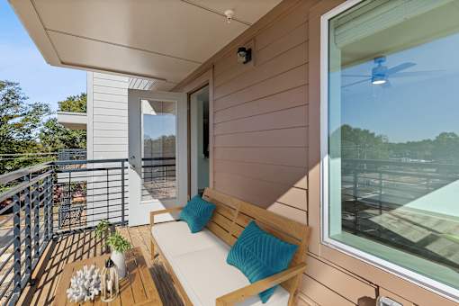 A balcony with a white couch and a blue pillow.