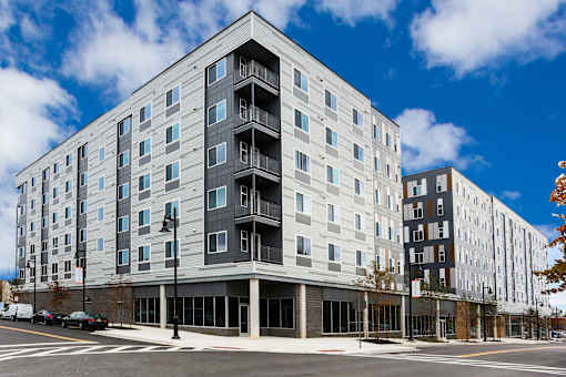A large, modern building with a mix of grey and white balconies.