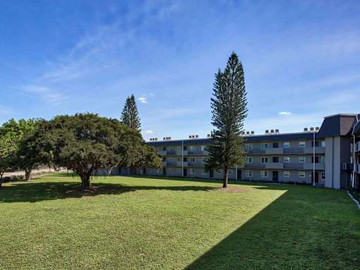 A grassy area in front of a building with trees.