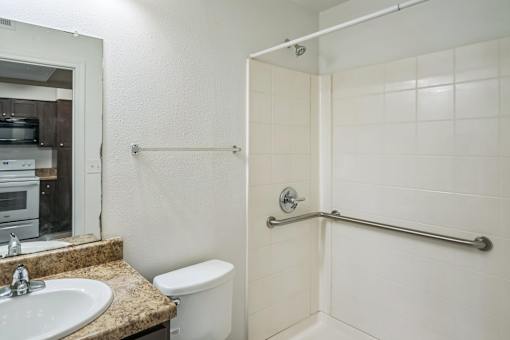 A bathroom with a white toilet, sink, and shower.