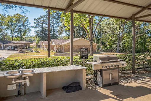 A covered outdoor kitchen area with a grill and sink.