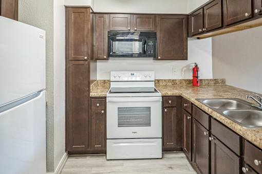 A kitchen with brown cabinets and a white stove top oven.