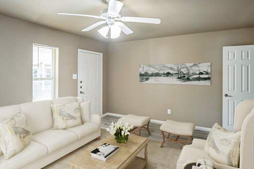 A living room with a white couch, a coffee table, and a painting on the wall.