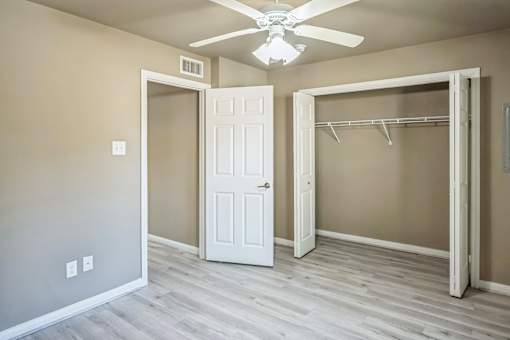 A room with a white door and a white closet with a hanger.