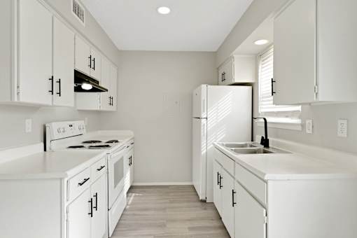 A white kitchen with a stove, oven, and refrigerator.