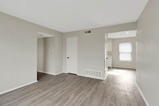 A room with light wood flooring and white walls.