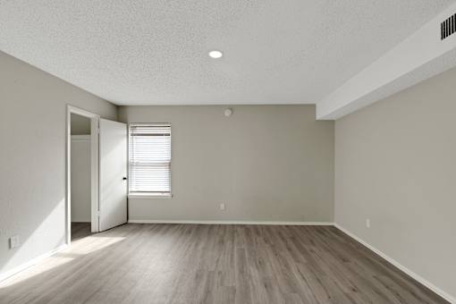 A room with a wooden floor and a door leading to another room.