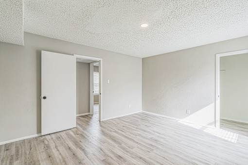 A room with a white door and a wooden floor.