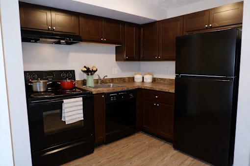 A kitchen with black appliances and wooden cabinets.