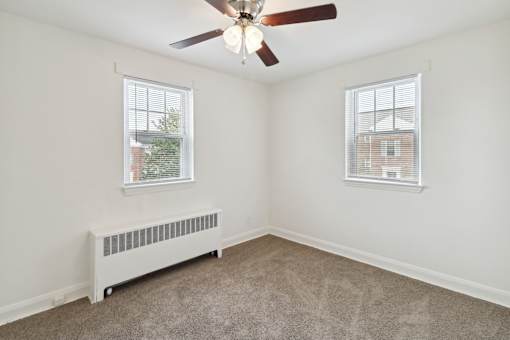 a bedroom with two windows and a ceiling fan