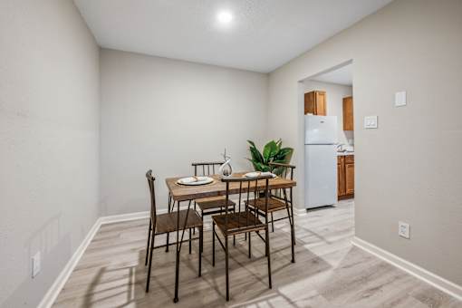 A dining room with a table set for two and a plant in the corner.