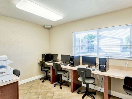 A room with a desk, chairs, and computers.