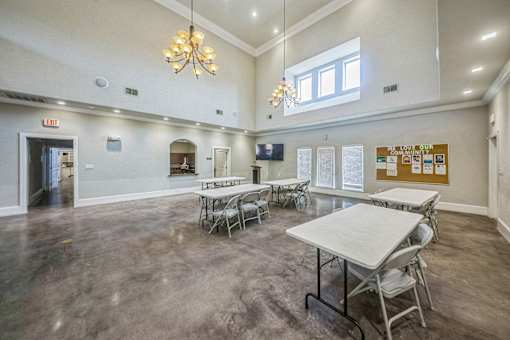 A room with tables and chairs and a white table in the middle.