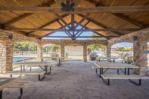 A covered outdoor seating area with tables and benches.