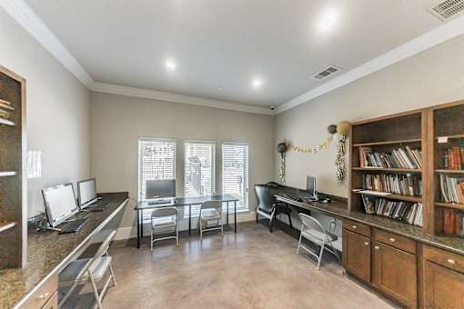 A room with a desk, chairs, and a bookshelf.