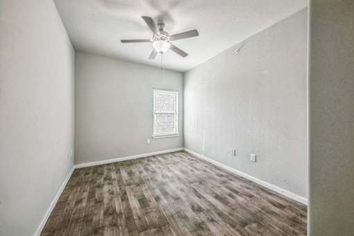 A room with a ceiling fan and wooden flooring.