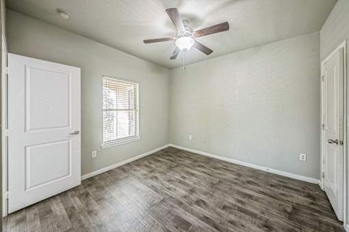 A room with a ceiling fan and a window with blinds.