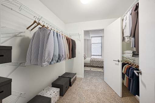 a walk in closet with clothes hanging on a rack and a door to a bedroom