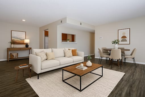 A living room with a white sofa, a coffee table, and a dining table with chairs.