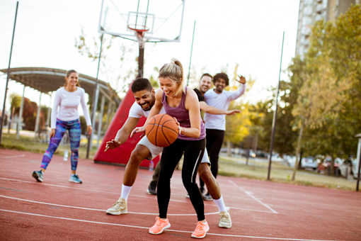 A group of people playing basketball on an outdoor court.